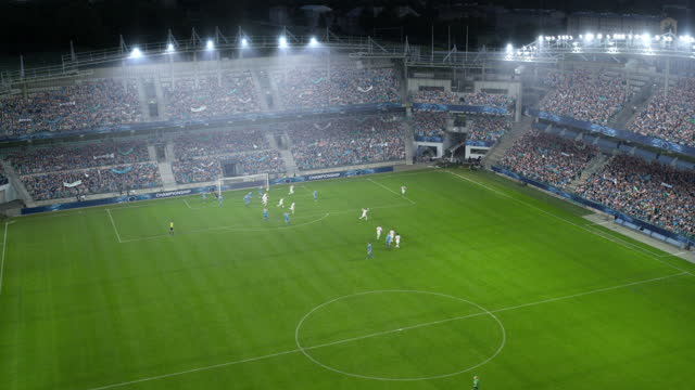 Aerial Arc Shot of a Whole Stadium with Soccer Championship Match. Teams Play, Crowds of Fans Cheer, Scoring Goal. Football Tournament, Cup Broadcast. Sport Channel Television Playback