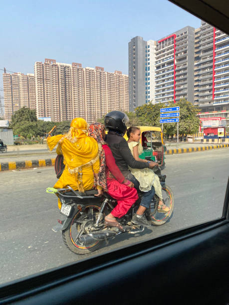 택시의 조수석 창문을 통해 본 고속도로에서 오토바이를 타는 4 명의 이미지, 충돌 헬멧을 쓴 한 사람, 위험한 운전 - india car indian culture indian ethnicity 뉴스 사진 이미지