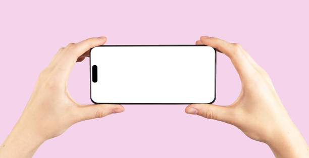 istock Mobile phone mockup, horizontal screen display mock up in hands, POV on pink 1443252065