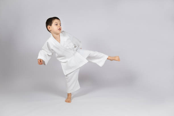 istock A little boy in a kimono practices karate on a white background, kicking forward. 1443252241