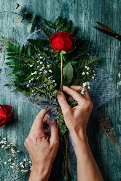 istock man is arranging a bouquet with red roses 1443252723