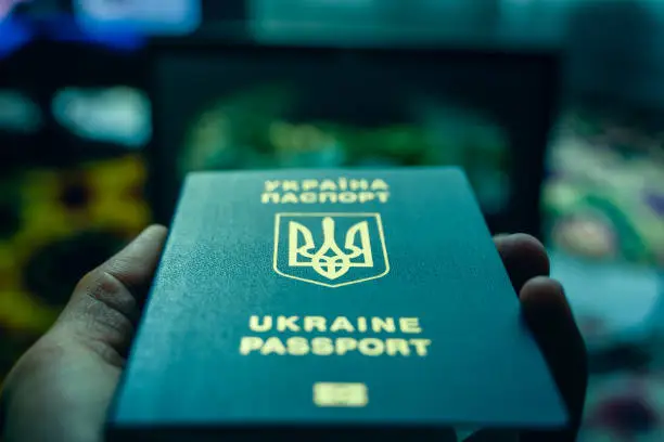 Photo of Ukrainian biometric passport in hand close-up in cold blue colors