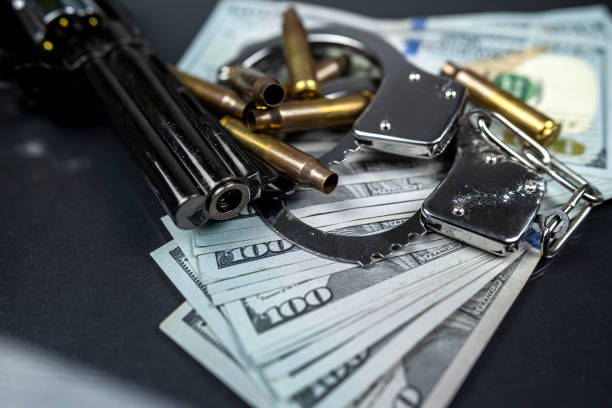 pistola y balas de pistola esparcidas y enrolladas billetes de dólar americano sobre mesa de vidrio negro. - gun currency crime mafia fotografías e imágenes de stock