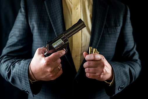 man in a suit holding a gun as a secret agent isolated on a black background. The concept of a man with a gun. hands with a revolver in front of the chest