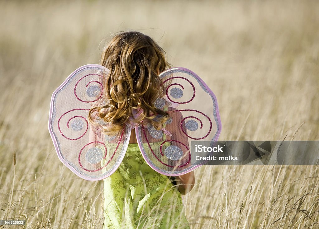 A little girl in a field wearing butterfly wings Little girl with butterfly wings and magic wand Butterfly - Insect Stock Photo