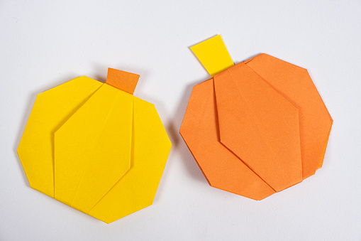 Halloween DIY Origami - Yellow and Orange Paper Pumpkins on a White Background.