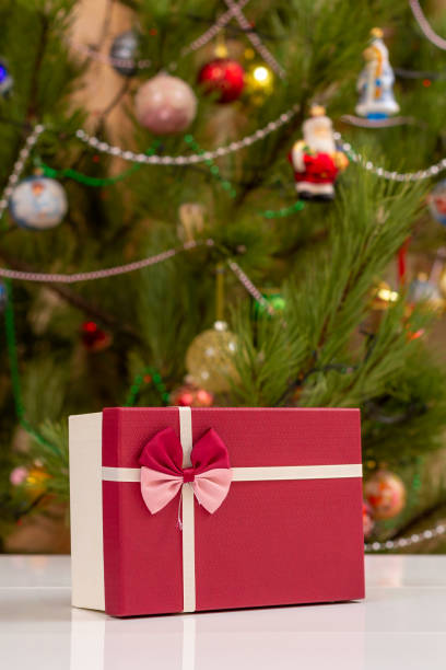 istock Gift box with bow and blurred Christmas tree with toy balls. 1443258372