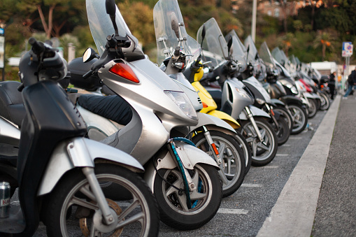 many scooters and motorcycles are parked in a long row