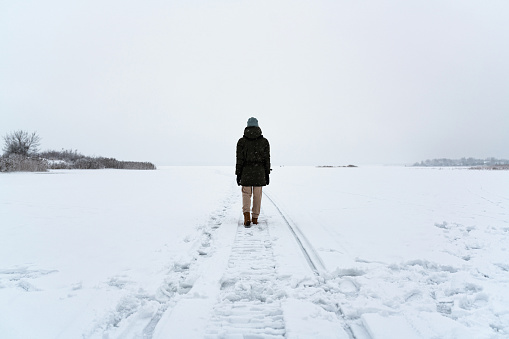 Woman walking alone in misty winter field. Solitude concept