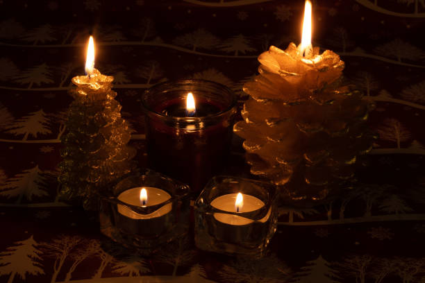 photo of lit candles of different shapes on a red background