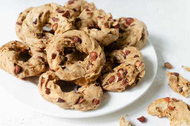 istock Tarallas with roasted almonds on a white plate on a white background. Delicious Neapolitan pastries. Traditional Italian snacks. Horizontal orientation. 1443268959