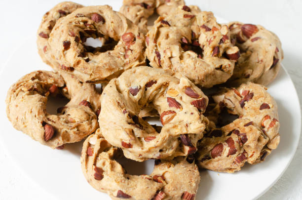 istock Tarallas with roasted almonds on a white plate on a white background. Delicious Neapolitan pastries. Traditional Italian snacks. Top view. Horizontal orientation. Close up 1443268962