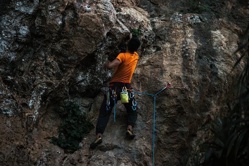 One young man, free climber, with a rope climbing on the rock mountain in nature.