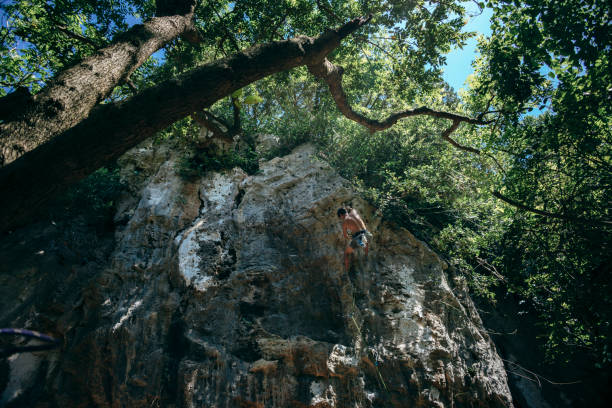 Young man, free climber, with a rope climbing on the rock mountain in nature.