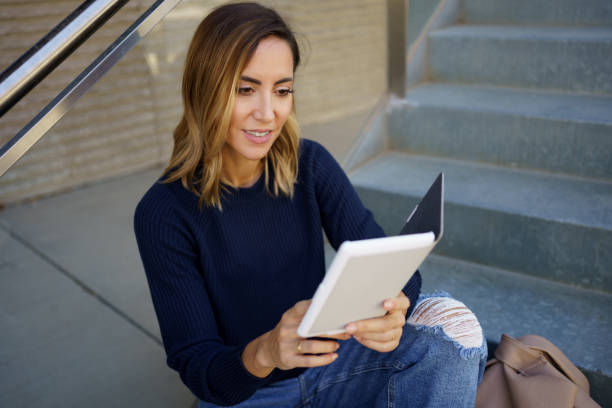istock Positive female smiling and reading e book 1443270803