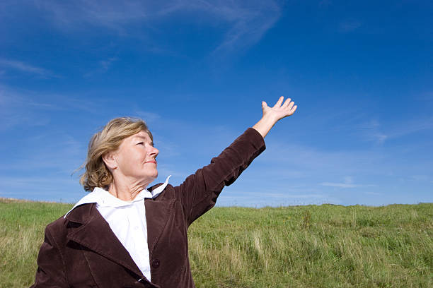 Friendly woman pionting at the sky stock photo