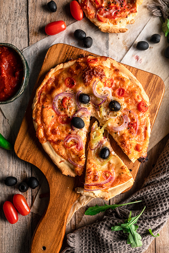 Rustic homemade pizza on wooden base