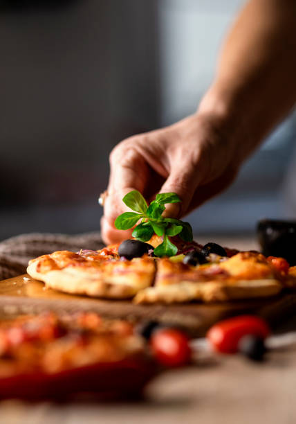 Top view of provolone and mozzarella cheese pizza with fresh basil leaves, black olives and anchovies.