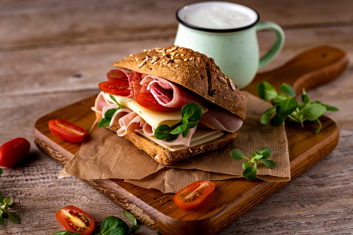 Delicious sandwich with prosciutto ham, cheese and vegetables