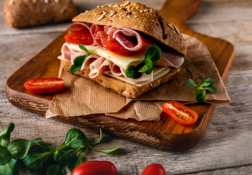 Delicious sandwich with prosciutto ham, cheese and vegetables