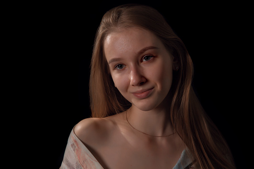 Enchanting young teenage girl in a off shoulder shirt  - black background