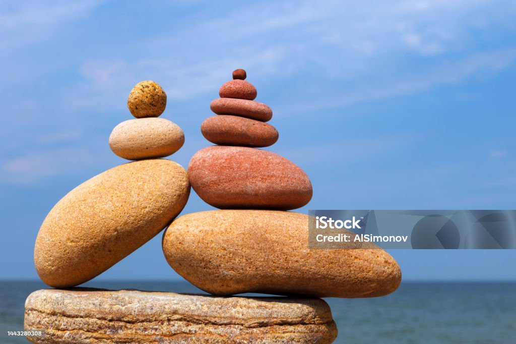 Two Rock zen pyramids of colorful pebbles on a beach on the background of the sea. Two Rock zen pyramids of colorful pebbles on a beach on the background of the sea. Concept of Life balance, harmony and meditation. Balance Stock Photo
