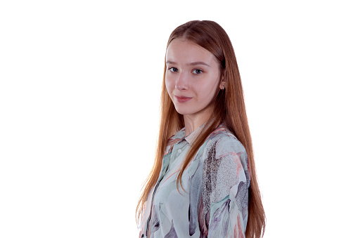 Charming young girl in a blue shirt stands sideways in front of white background - potrait photo