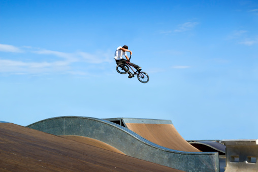 Thrilling BMX jump off a ramp in a skate park on a summer's day.