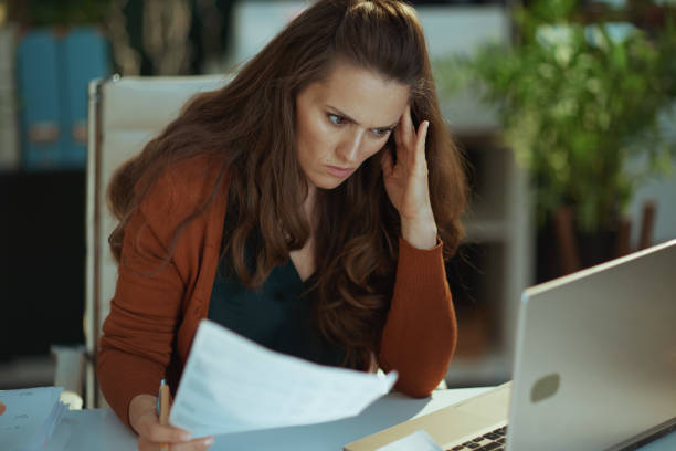 sad business owner woman in green office working with documents stock photo