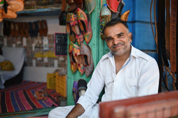 Rajasthani leather-smith sitting in a leather shop and smiling at Camera. Photographed in Jodhpur, Rajasthan