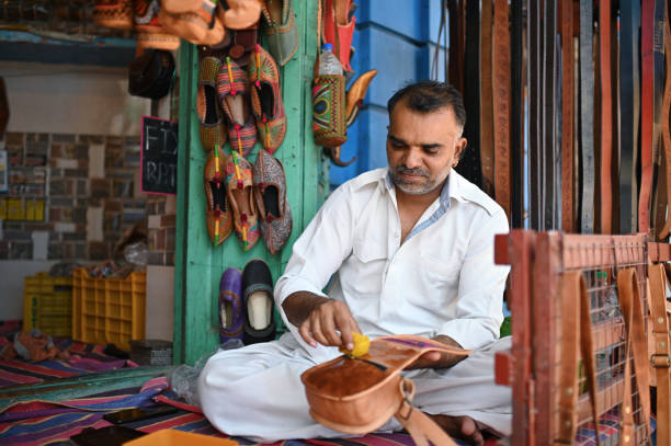 Mid-adult man polishing leather hand bag in a shop in Jodhpur, Rajasthan