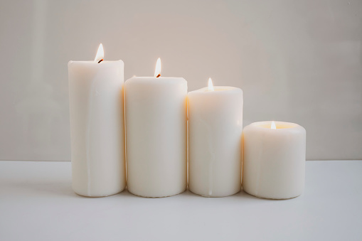 Large burning candles on the background of a white wall.