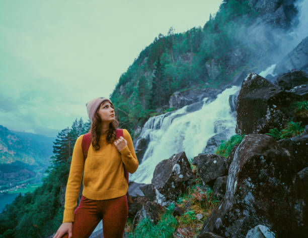 istock Woman standing near the powerful  waterfall in mountains in Norway 1443286708