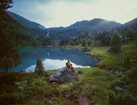 Young Caucasian woman sitting on the background of the lake in Norway