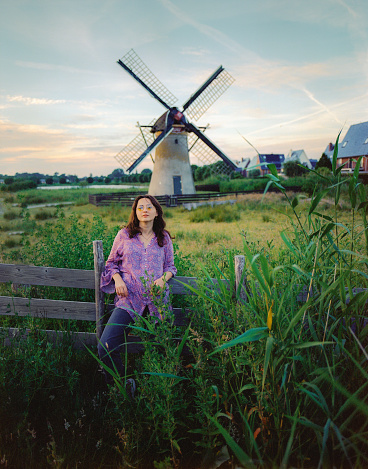 Young Caucasian woman standing near the windmill in The Netherlands