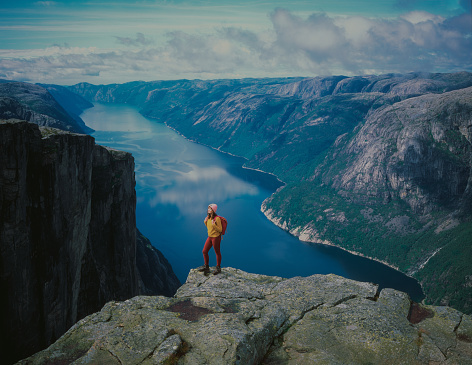 Young Caucasian woman hiking in mountains on the background of Lysefjorden