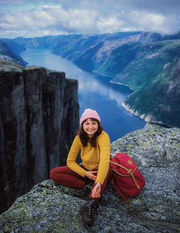 Young Caucasian woman sitting on Preikestolen and looking at view