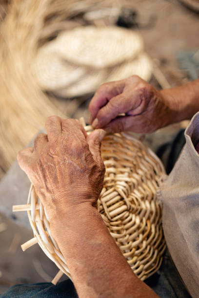 Close up caption of man hands weaving wicker for a craft basket. stock photo