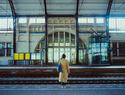 Young Caucasian woman waiting for the train on railway station in Delft