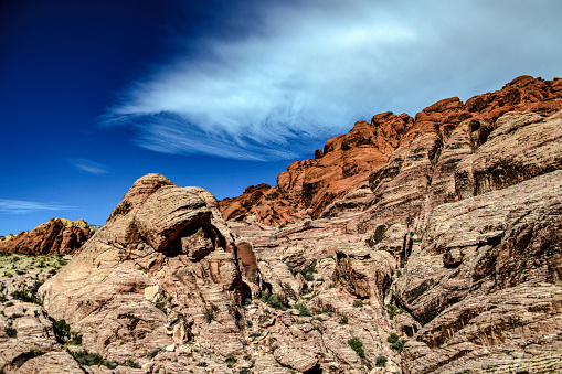 Very distinct color change between the lower and upper rocks of Red Rock National Conservation Area with a beautiful cloudy blue sky.