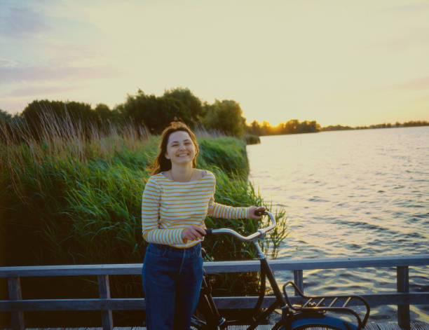 mujer con bicicleta cerca del lago al atardecer - dutch culture fotos fotografías e imágenes de stock