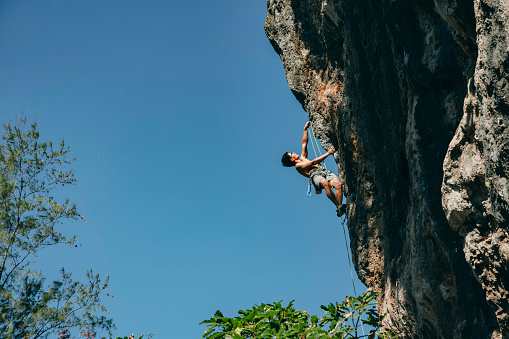 One young man, free climber, with a rope climbing on the rock mountain in nature.