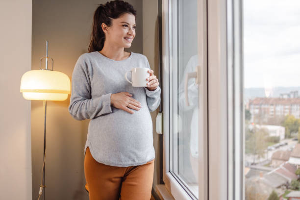 istock Beautiful pregnant woman relaxing by window 1443291321
