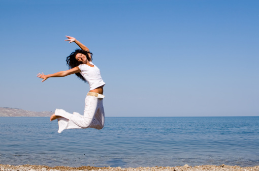 happy young woman is jumping in the beach