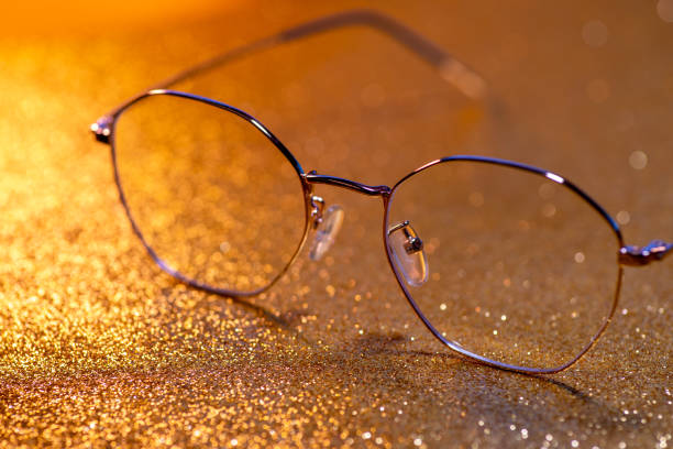 istock Gold-rimmed spectacles on lights background,Gold Glitter Sparkle Confetti Background 1443297721