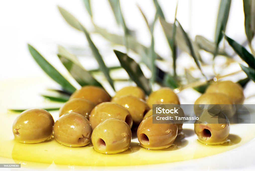 Olives and Olive Oil on white plate Olives and olive oil on plate isolated in warm natural light. Bright Stock Photo