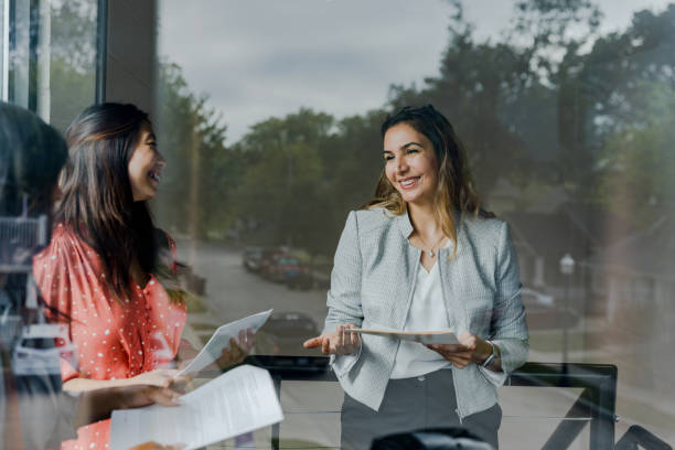 Businesswomen discuss documents during meeting Meeting together, three businesswomen smile as they discuss the documents. independence document agreement contract stock pictures, royalty-free photos & images