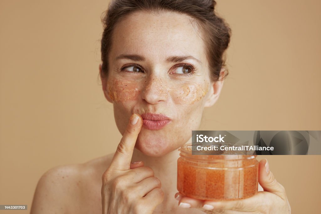 happy modern woman with face scrub happy modern middle aged woman with face scrub on beige background. Exfoliation Stock Photo