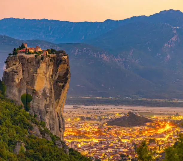 Beautiful view of Meteora monastery and illuminated cityscape against mountains during sunset