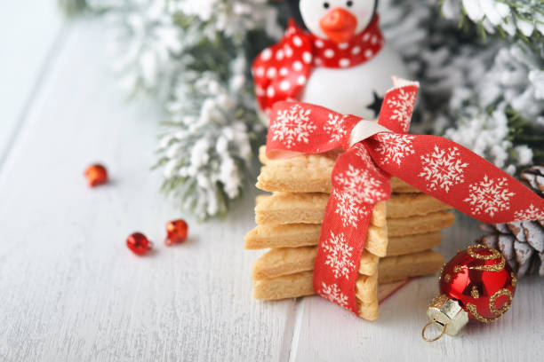 biscuits sablés de noël ou étoiles en pain d’épices avec ruban rouge, décoration festive, sapin, boules et guirlande lumineuse. cookies traditionnels allemands. traditions de célébration de noël culinaires familiales. - cookie christmas shortbread christmas tree photos et images de collection